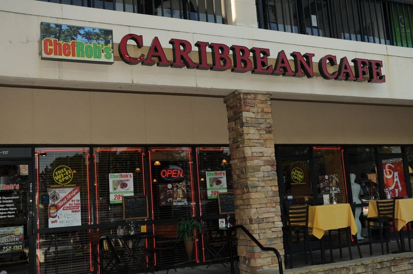 Chef Rob's Caribbean Cafe storefront with an "OPEN" sign, outdoor seating, and promotional posters.