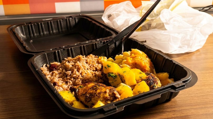 Takeout container with rice, chicken, and yellow potatoes, with a plastic fork and bag.