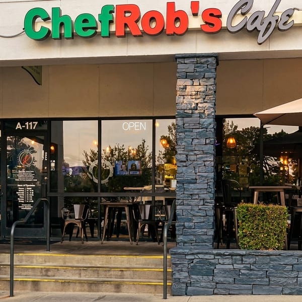 Exterior of Chef Rob's Cafe & Bar with outdoor seating, a menu board, and a woman.
