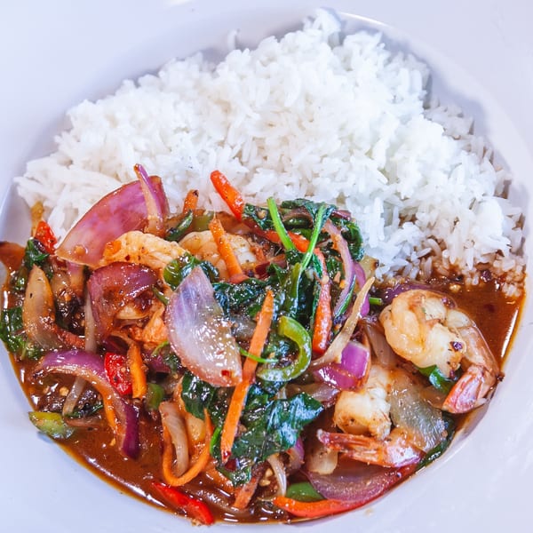 Shrimp stir-fry with red onions, carrots, and green peppers, served with white rice.